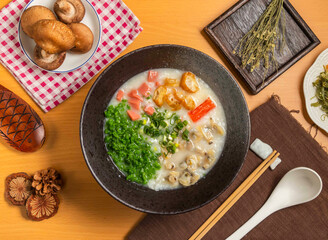 Emerald Clam Porridge with mushroom,chopsticks and spoon served in bowl isolated on wooden table top view of taiwan food