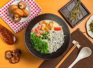 Jade fish porridge with mushroom,chopsticks and spoon served in bowl isolated on wooden table top view of taiwan food