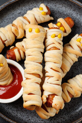 Halloween mummies sausages in dough with ketchup. Halloween party snack.