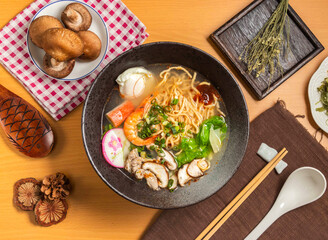 Pot roasted pasta with shrimp,beetroot,noodles mushroom,chopsticks and spoon served in bowl isolated on wooden table top view of taiwan food