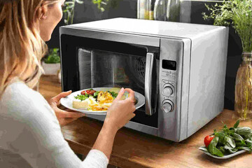 Woman Reheating Food in Microwave - Kitchen Appliances