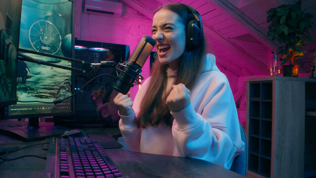 Cheerful Caucasian woman winner influencer typing computer playing game Internet addict e-sport gamer female blogger smile win match victory girl streamer shout yes rejoice at home video blog stream