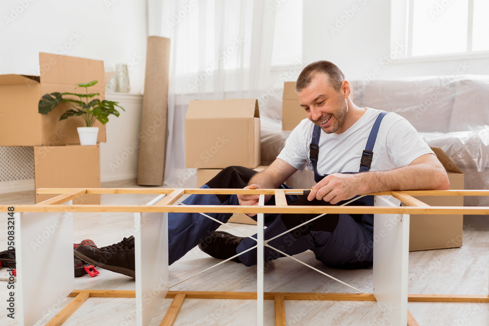 Poster happy furniture assembler in blue coverall fixing shelf with screwdriver providing assembling and tr