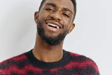 Obraz premium Cheerful bearded man in red and black sweater smiling warmly, standing against a plain white background
