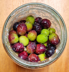 Glass jar with olives in various shades of green and purple with sea salt