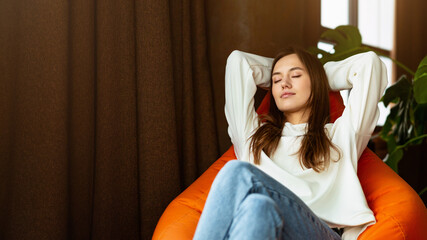 Break from work concept. Girl freelancer with closed eyes relaxing on bag chair