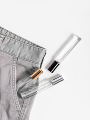 Three glass bottles of perfume in pocket of pants on white background