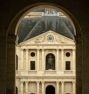 Classic architectural facade with clock and statue in Paris.