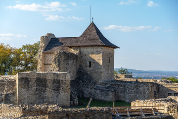 The Castle in Suceava, a historical stone structure with a sloped roof, set against a clear blue sky, highlighting its architectural significance.