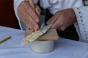 Romania, Suceava, September 21, 2024. A craftsman meticulously carving intricate designs on a wooden spoon, demonstrating traditional woodworking skills and attention to detail.