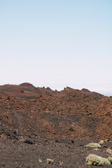 Vulkanische Landschaft mit roten und schwarzen Lavafelsen unter klarem Himmel