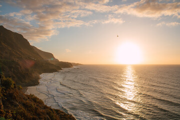 Atemberaubender Küstenblick bei Sonnenuntergang mit Bergen und Meer