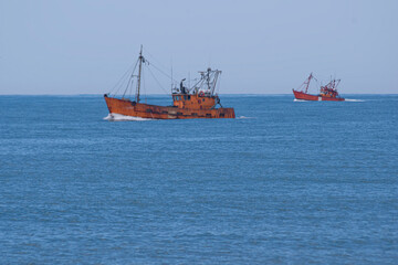 Orange fishing ship's sailing on the blue sea