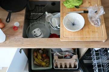 Kitchen mess. A top down view of a kitchen counter filled with dirty cutlery. Dishwasher door open.