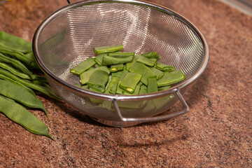 Flat green bean cut and uncut in a metal strainer