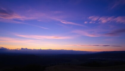 Obraz premium a view of a sunset over a valley with a few clouds