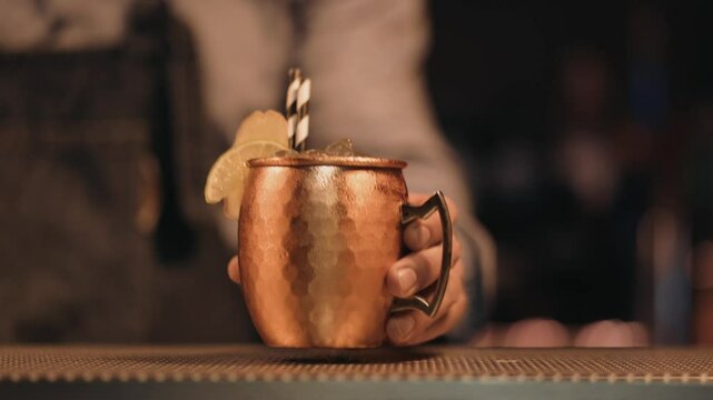 Bartender serving a classic Moscow Mule cocktail in a copper mug
