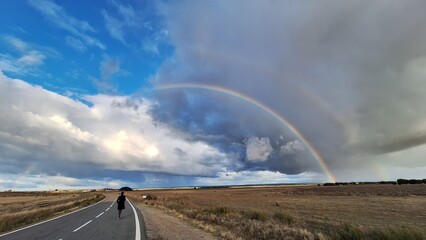 a person observing a rainbow after the storm from a road in Castilla y Le&oacute;n, Spain