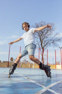 Young man rollerblading with headphones in urban park