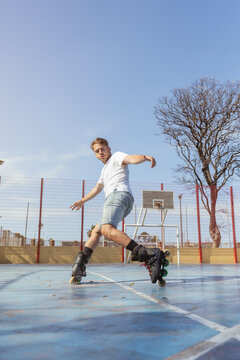 Young man rollerblading on a sunny outdoor court