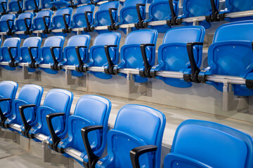 A long row of modern blue chairs with folding seats in a hall