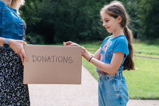Young girl putting stuff into a donation box
