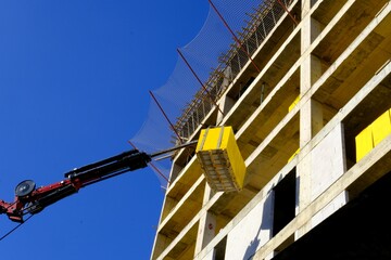 Concrete lifting crane transports concrete blocks to the building under construction. Housing...
