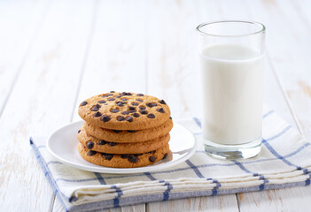 Chocolate chip cookies and milk on a white table, close up.