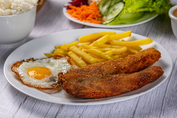 breaded chicken with eggs, fries and vegetables