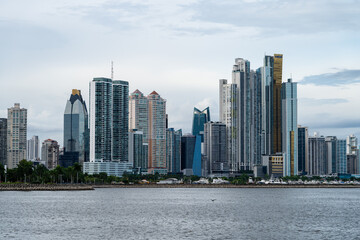 Cluster of modern skyscrapers in Panama City, with boats and park underneath. Viewed from across the water