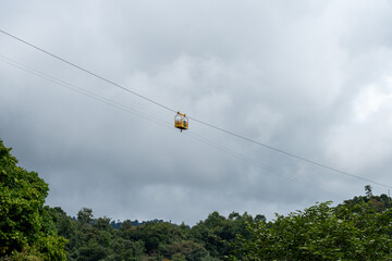 Small yellow cablecar suspended high above the canopy in the mindo valley