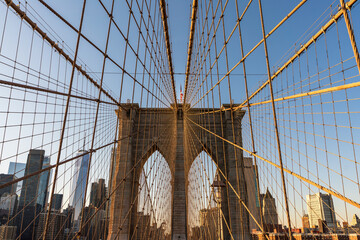 View of the Brooklyn Bridge's Gothic Granite Tower and Cables with US Flag on top and 1875 year visible