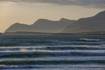 Obraz premium Mystische Stimmung am Strand von Keel Beach auf der Halbinsel Achill Island in Irland. Wellen und Berge, etwas nebel und die Abendämmerung.