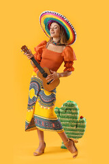 Pretty young woman in sombrero on yellow background