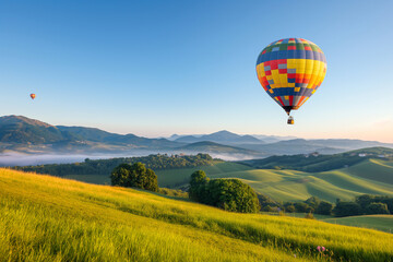 Obraz premium A colorful hot air ballon floating above the green hills at sunrise, symbolising freedom and adventure in travel and vacation planning.