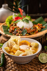 Vegetable soup in a white porcelain bowl with other food beside it