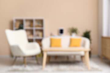 Interior of modern living room with sofa and bookshelf near beige wall, blurred view