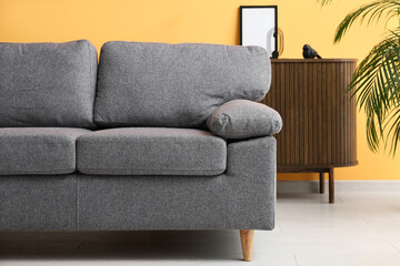 Comfortable sofa near orange wall in stylish living room