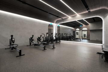 Modern gym setting with equipment in elaborate lighting and a large mirror. Health and wellness room for fitness and strength training. 