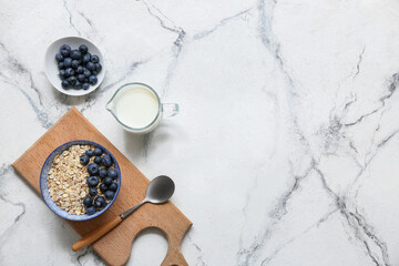 Bowl with raw oatmeal and berries on light background