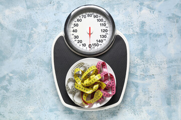 Scales and measuring tapes on light blue grunge background. Weight loss concept