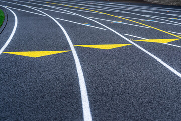 Close up of yellow exchange zone markings on a new black running track with white lane lines.	