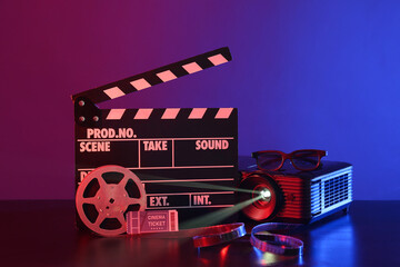 Video projector with movie clapper, cinema ticket and film reel on dark background