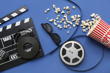 Movie clapper with glasses, popcorn and film reels on blue background