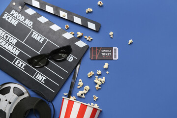 Movie clapper with cinema ticket, glasses, popcorn and film reels on blue background