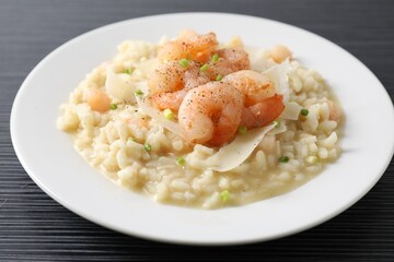 Delicious risotto with shrimps and cheese on black table, closeup