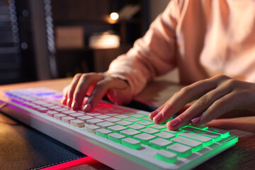 Fototapeta premium Girl using computer keyboard at wooden table indoors, closeup