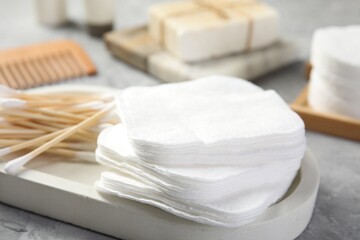 Clean cotton pads and swabs on grey table, closeup