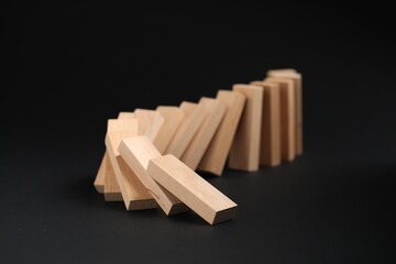 Domino effect. Wooden blocks falling on black background