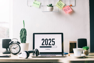 Office desk with 2025 loading bar on laptop screen for happy new year concept